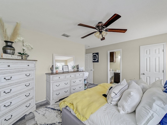 bedroom with ceiling fan, ensuite bath, and light hardwood / wood-style flooring