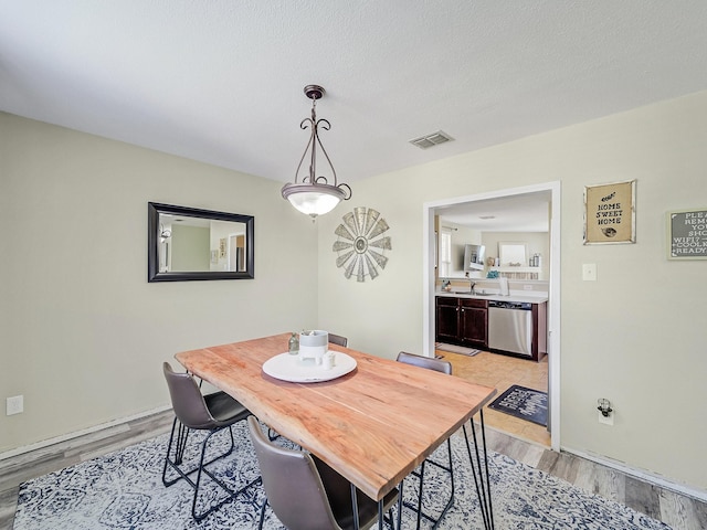 dining space featuring sink, light hardwood / wood-style flooring, and a textured ceiling