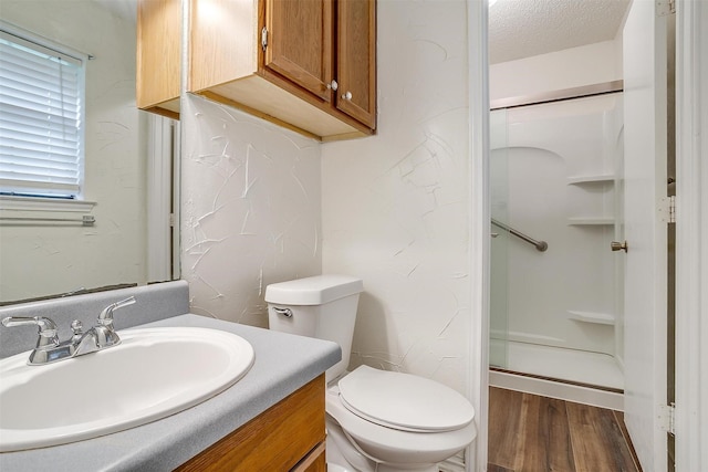 bathroom with walk in shower, vanity, toilet, hardwood / wood-style flooring, and a textured ceiling