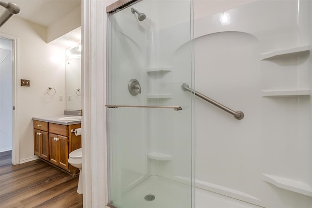 bathroom featuring walk in shower, vanity, toilet, wood-type flooring, and a textured ceiling