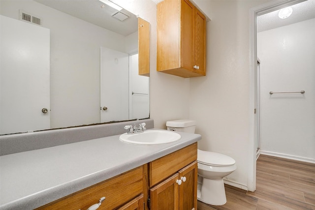 bathroom featuring toilet, vanity, a shower with door, and hardwood / wood-style flooring