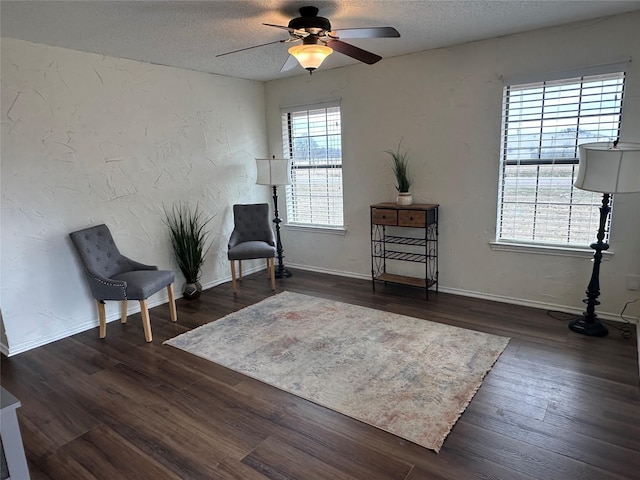 living area with a textured ceiling, dark wood-type flooring, and ceiling fan