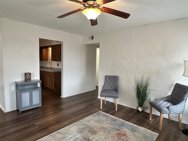 sitting room featuring a textured ceiling, dark wood-type flooring, ceiling fan, and sink