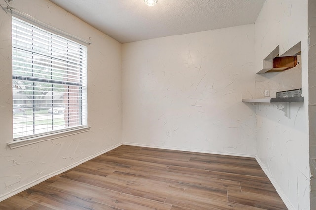 unfurnished room with hardwood / wood-style floors and a textured ceiling