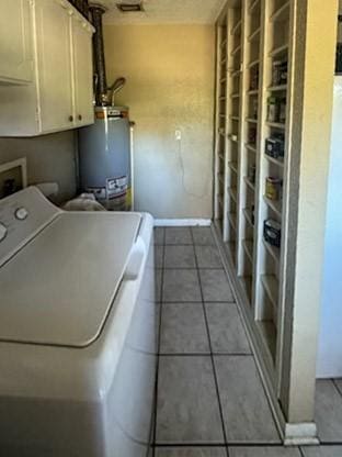washroom with water heater, tile patterned floors, cabinet space, and washer / clothes dryer