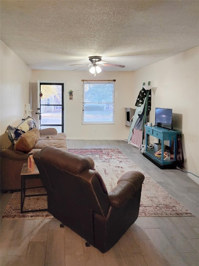 living area with a textured ceiling, ceiling fan, and wood finished floors
