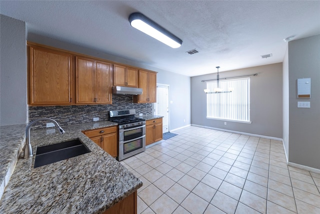 kitchen featuring dark stone countertops, double oven range, hanging light fixtures, sink, and light tile patterned floors