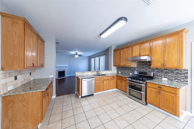 kitchen featuring decorative backsplash, sink, light stone counters, and stainless steel appliances