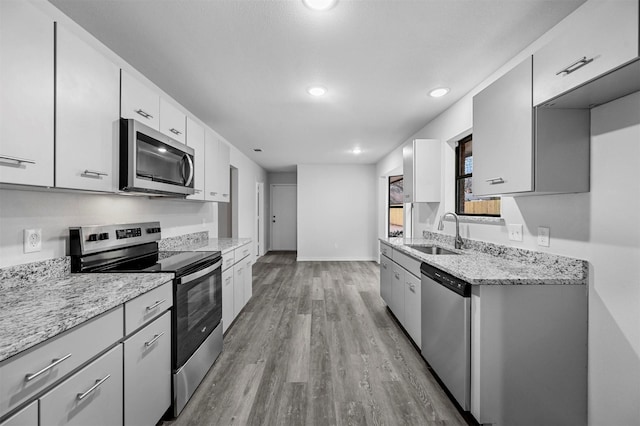 kitchen featuring light stone counters, sink, white cabinetry, and stainless steel appliances