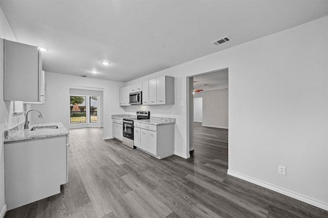 kitchen featuring sink, white cabinetry, light stone countertops, stainless steel appliances, and dark hardwood / wood-style flooring