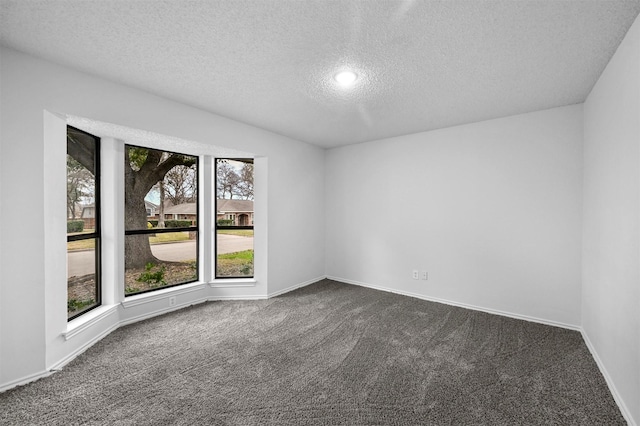 empty room featuring dark carpet and a textured ceiling