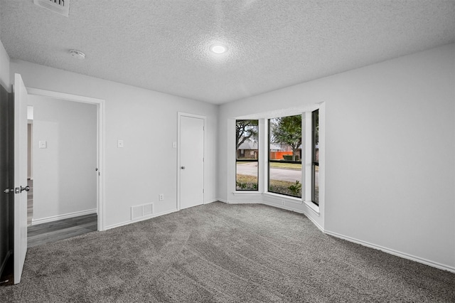 carpeted empty room with a textured ceiling