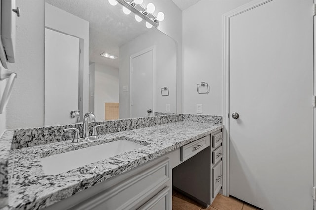 bathroom with a textured ceiling, vanity, and tile patterned flooring