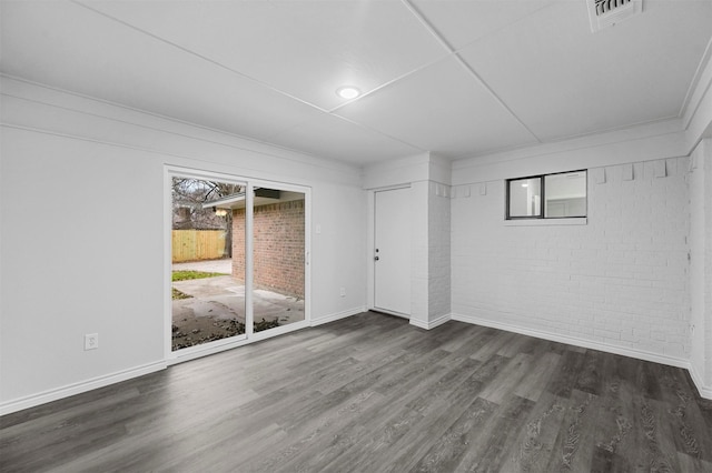 spare room with brick wall and dark hardwood / wood-style flooring