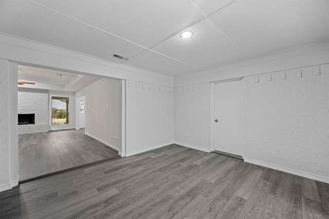 interior space featuring a fireplace, brick wall, and hardwood / wood-style flooring