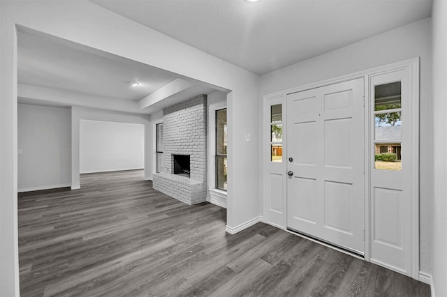 entrance foyer featuring dark wood-type flooring and a brick fireplace