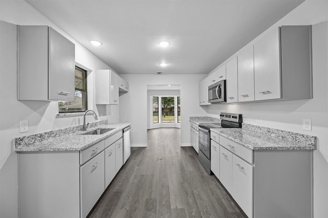 kitchen with white cabinets, appliances with stainless steel finishes, sink, and light stone counters