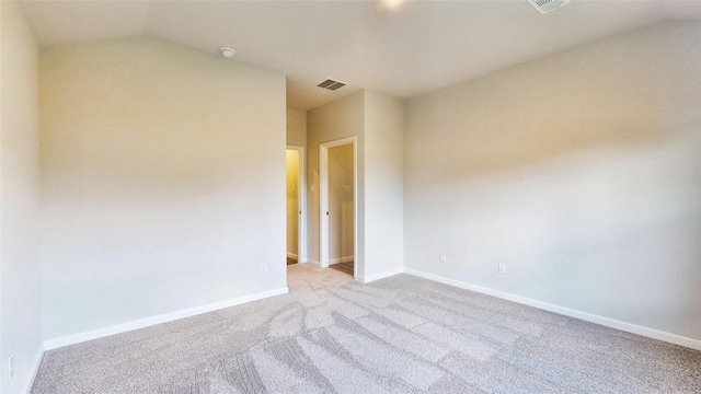 empty room featuring light colored carpet and vaulted ceiling