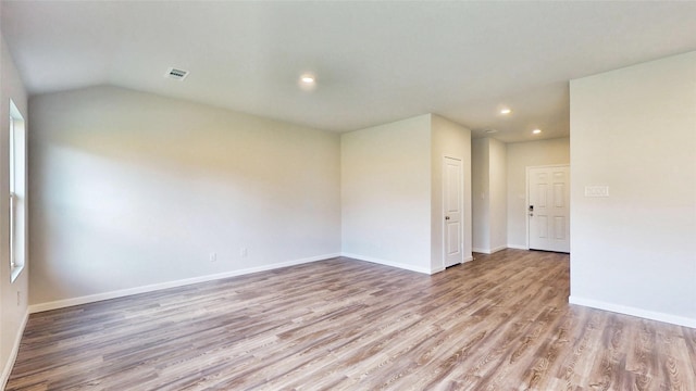 empty room with vaulted ceiling and light hardwood / wood-style flooring