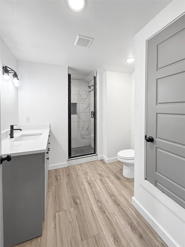 bathroom with wood-type flooring, an enclosed shower, vanity, and toilet