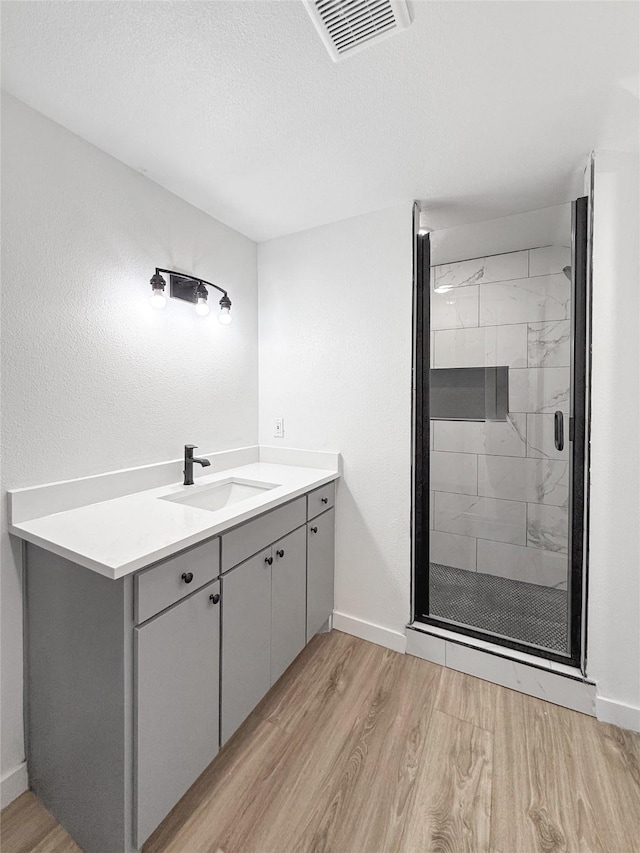 bathroom with vanity, a shower with door, a textured ceiling, and hardwood / wood-style floors