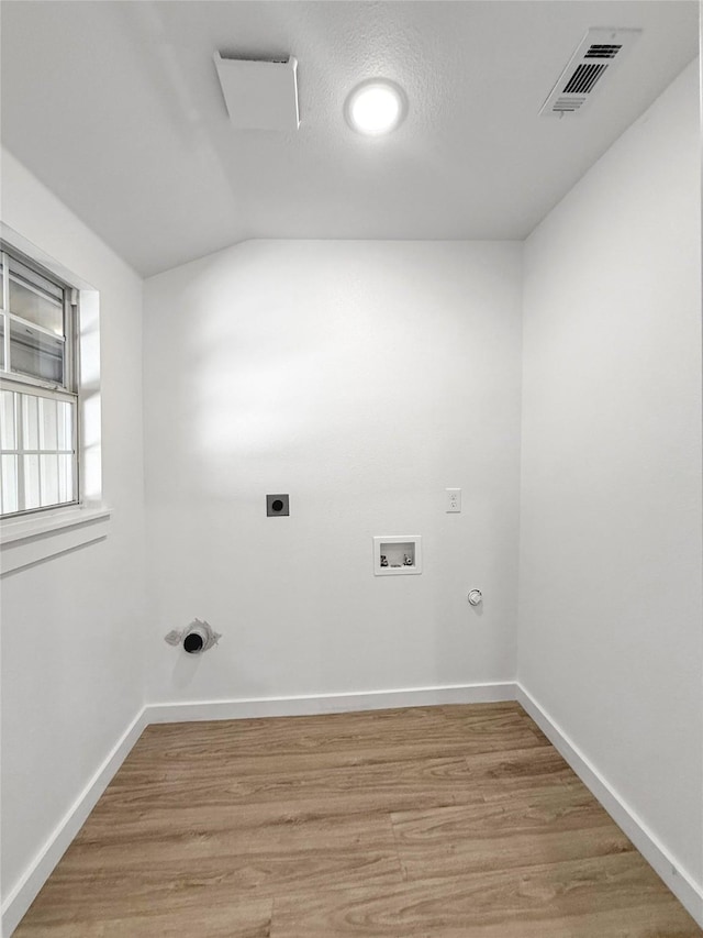 washroom with hookup for an electric dryer, hookup for a washing machine, a textured ceiling, light hardwood / wood-style flooring, and gas dryer hookup