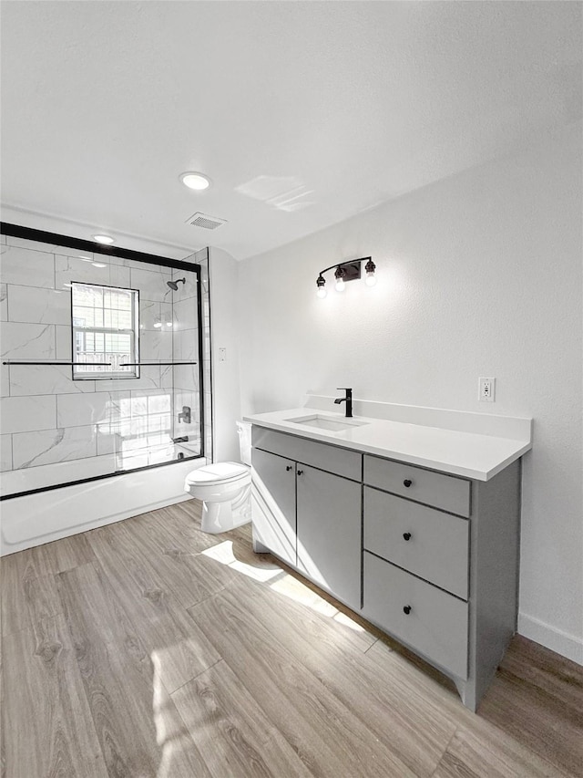 full bathroom with combined bath / shower with glass door, vanity, toilet, and hardwood / wood-style flooring