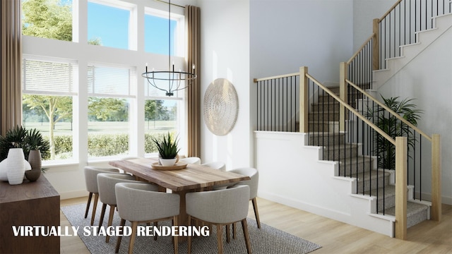 dining space featuring a towering ceiling, an inviting chandelier, and light hardwood / wood-style flooring