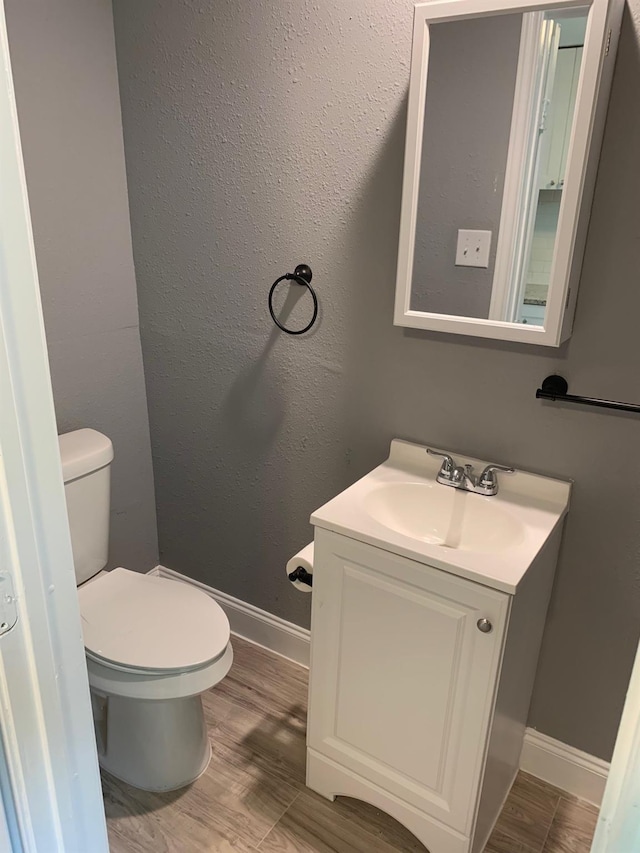 bathroom with hardwood / wood-style floors, toilet, and vanity