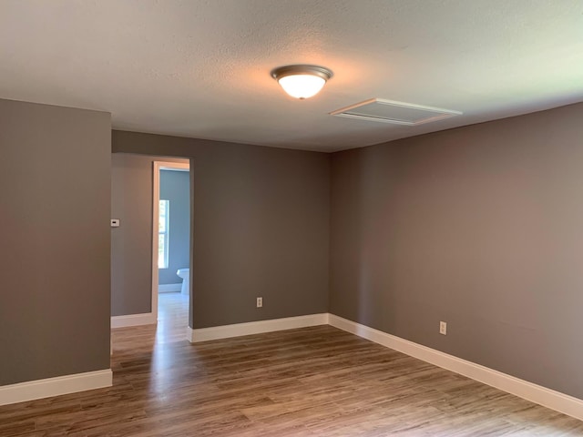 spare room with a textured ceiling and hardwood / wood-style floors