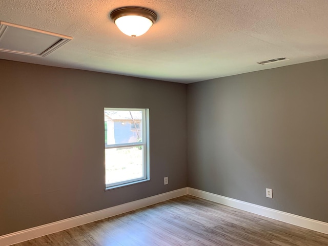 unfurnished room featuring a textured ceiling and hardwood / wood-style floors