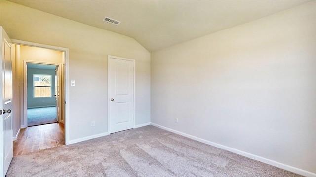 unfurnished bedroom with light carpet, a closet, and vaulted ceiling