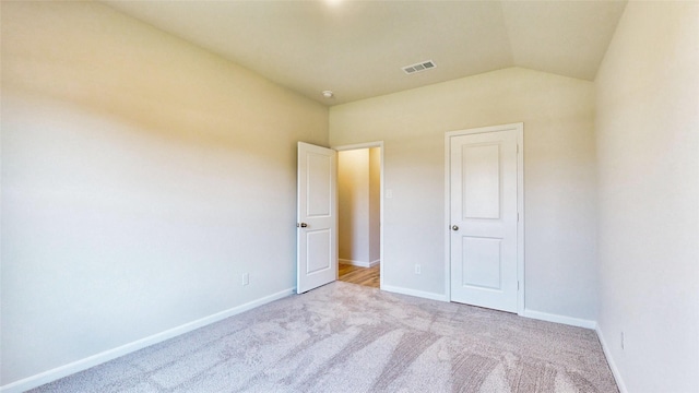 unfurnished bedroom featuring light carpet and vaulted ceiling