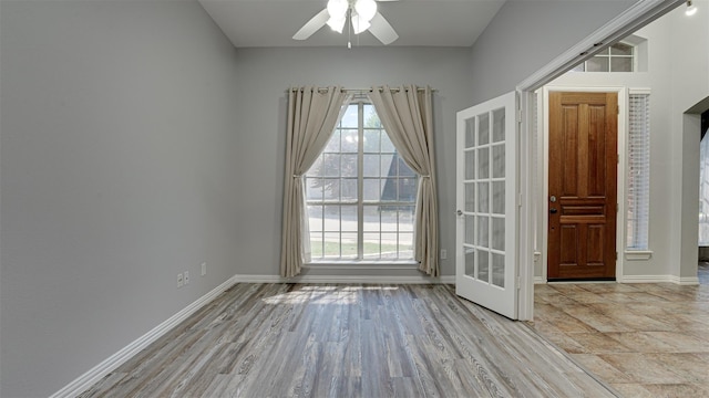 empty room with ceiling fan, light hardwood / wood-style floors, and french doors