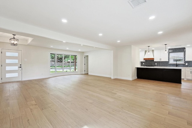 unfurnished living room featuring light hardwood / wood-style flooring and a notable chandelier