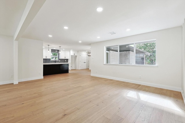 unfurnished living room featuring light wood-type flooring and sink