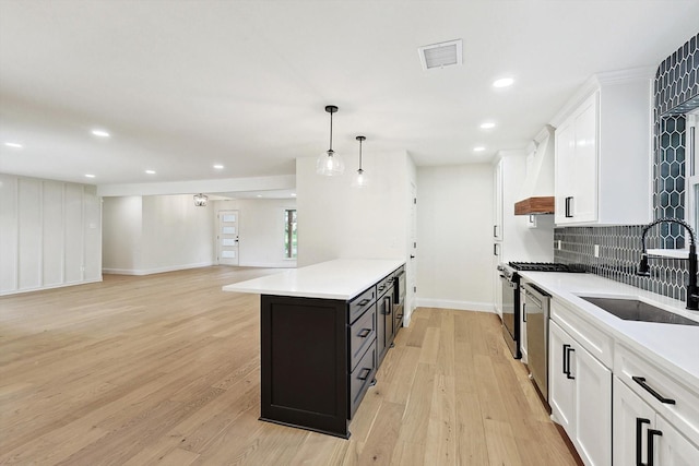 kitchen with light hardwood / wood-style flooring, white cabinets, hanging light fixtures, and sink