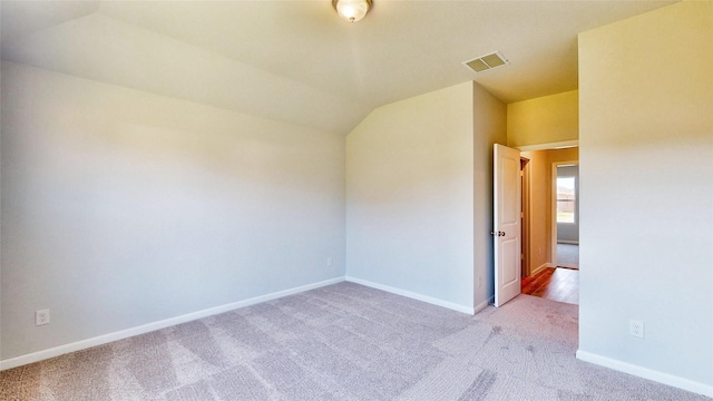 carpeted empty room featuring vaulted ceiling