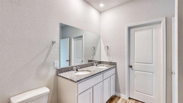 bathroom featuring toilet, hardwood / wood-style flooring, and vanity