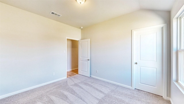 unfurnished bedroom with light colored carpet and lofted ceiling