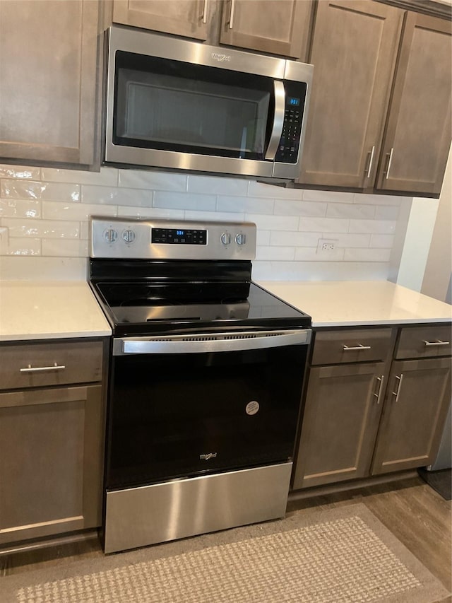 kitchen featuring tasteful backsplash, light hardwood / wood-style flooring, appliances with stainless steel finishes, and dark brown cabinetry