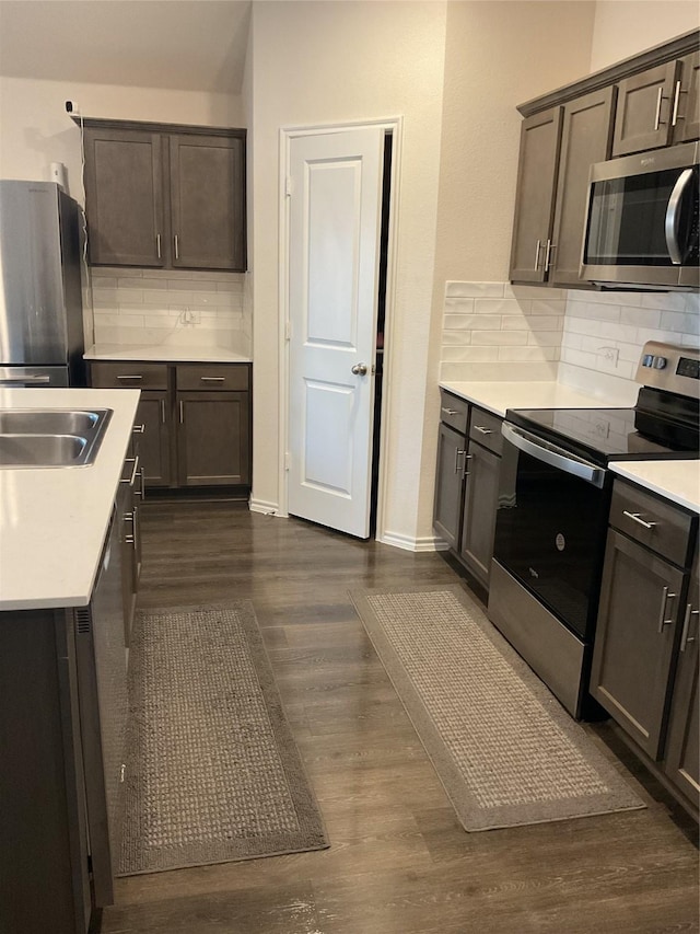 kitchen featuring appliances with stainless steel finishes, decorative backsplash, dark hardwood / wood-style floors, and dark brown cabinetry