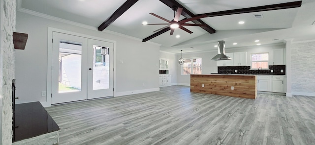 kitchen featuring tasteful backsplash, lofted ceiling with beams, white cabinets, french doors, and island range hood