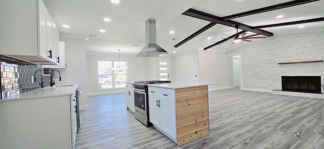 kitchen featuring white cabinetry, stainless steel range with gas cooktop, island exhaust hood, vaulted ceiling with beams, and a kitchen island