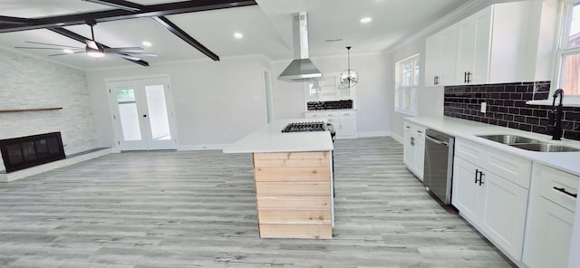 kitchen with pendant lighting, stainless steel dishwasher, sink, white cabinetry, and island range hood