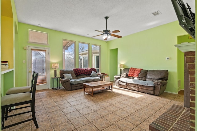 living room featuring ceiling fan, a wealth of natural light, a textured ceiling, and light tile patterned flooring