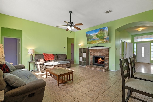 tiled living room featuring ceiling fan and a fireplace