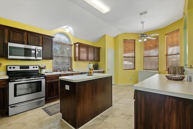 kitchen featuring stainless steel appliances, a center island, vaulted ceiling, a wealth of natural light, and sink