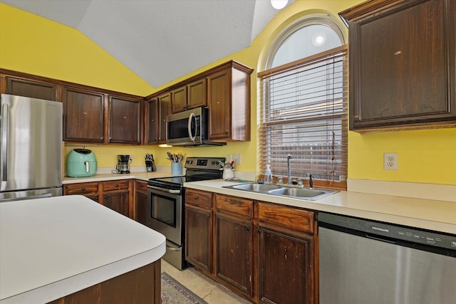 kitchen featuring vaulted ceiling, appliances with stainless steel finishes, sink, and dark brown cabinets