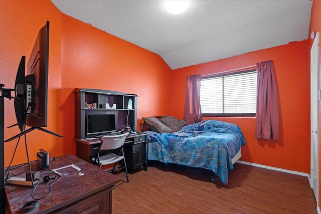 bedroom featuring vaulted ceiling, a textured ceiling, and hardwood / wood-style flooring